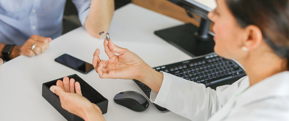 Professional in clinic showing couple hearing aid
